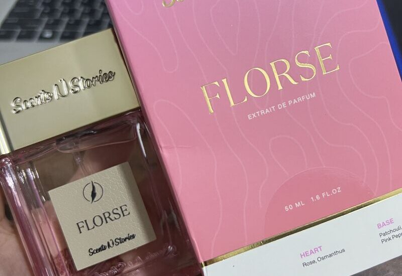 Aesthetic bottle of Florse Scents N Stories placed on a marble counter with delicate flowers around, lit by soft daylight.